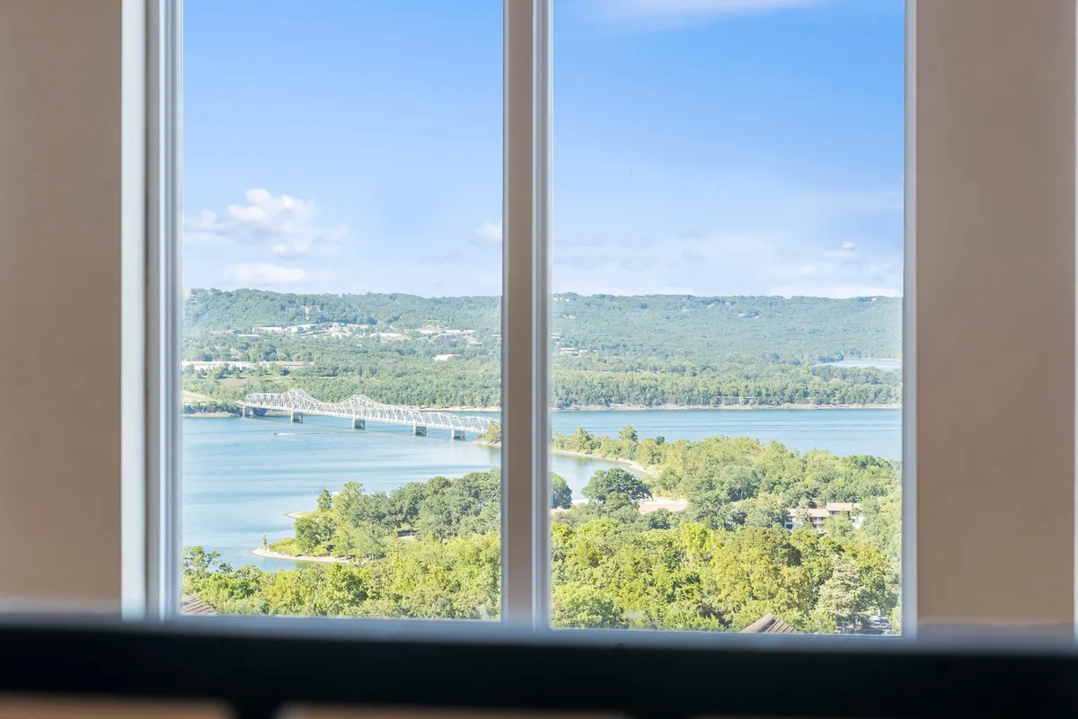 A tranquil view of a river, bridge, and lush landscape seen from a comfortable vantage point. The expansive sky and peaceful surroundings evoke the sense of exploration and natural beauty available just outside the property.