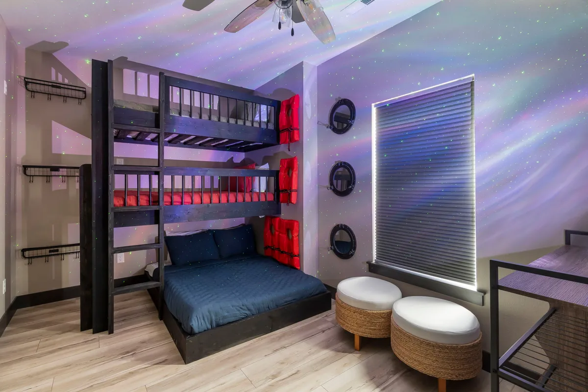 A cheerful bunk room with multiple bunk beds adorned in colorful bedding and a whimsical starry ceiling effect. The playful decor and cozy setup create the perfect environment for kids' sleepovers and fun-filled nights.