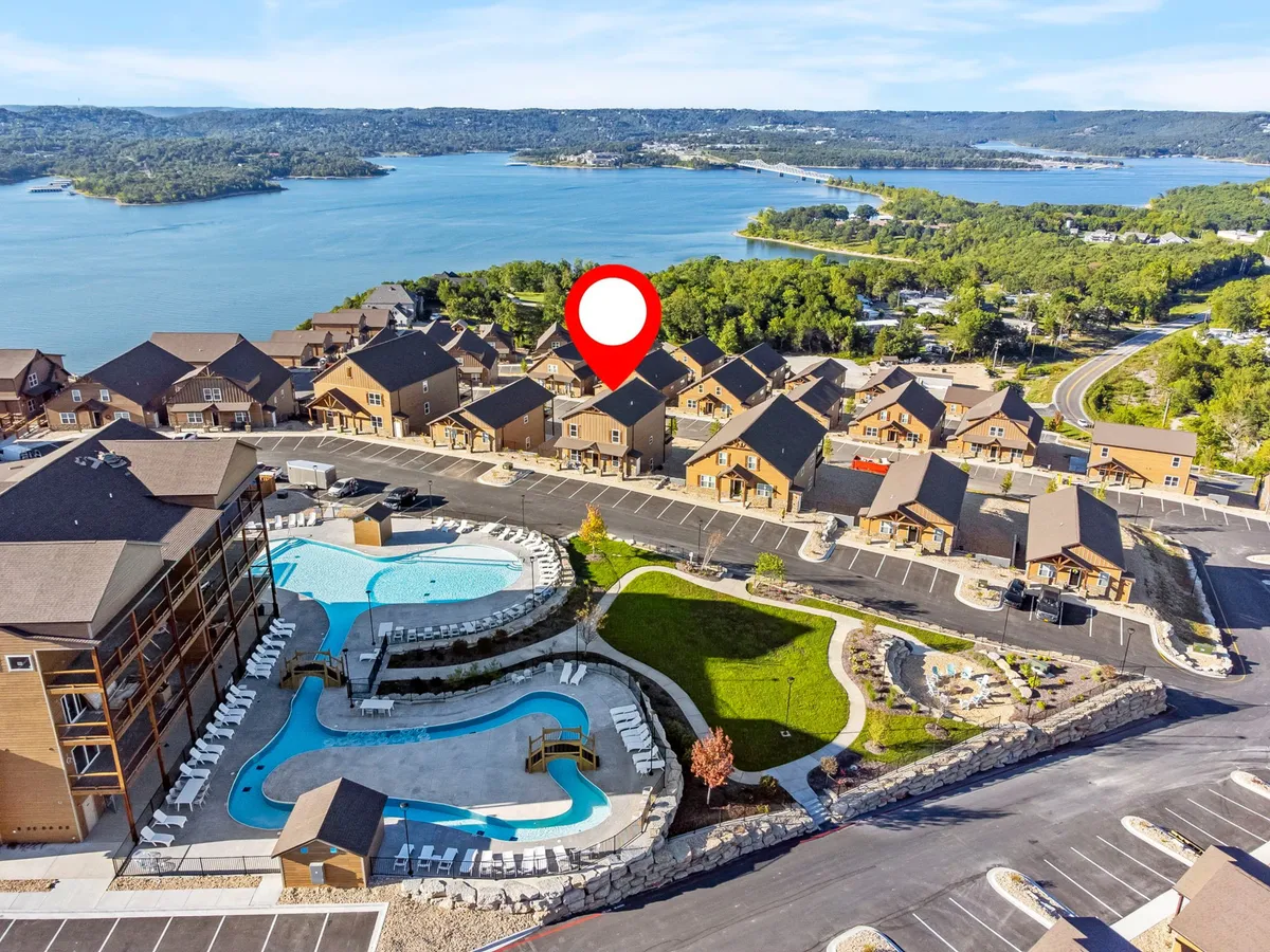 This exterior shot features a luxurious swimming pool with lounge chairs, set against a backdrop of the lake and landscaped resort grounds. The pool area is adjacent to residential buildings, all surrounded by natural beauty and open skies—perfect for morning walks or outdoor relaxation with pets.