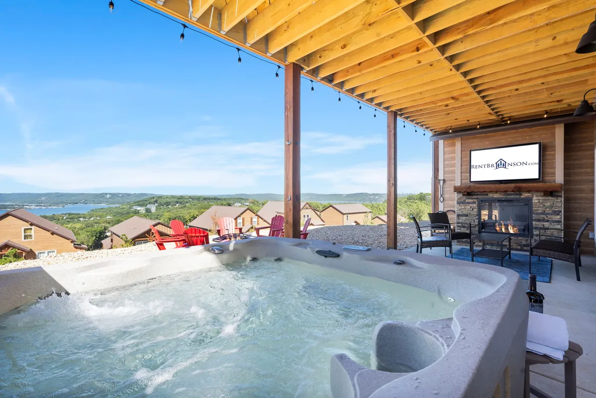 An exterior scene showing a private hot tub area complete with outdoor seating, a fireplace, and scenic landscape views. The ambiance is tranquil and inviting, perfect for unwinding after adventurous days or capping off game-filled evenings.