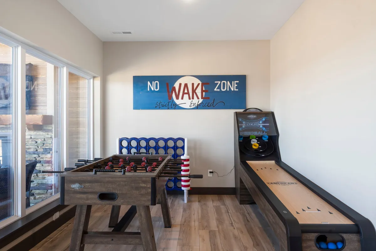 This interior shot spotlights a foosball table and shuffleboard table in a relaxed recreation space, accompanied by a decorative sign and cozy ambiance. The setup is ideal for hosting friendly competitions and socializing in a welcoming environment.