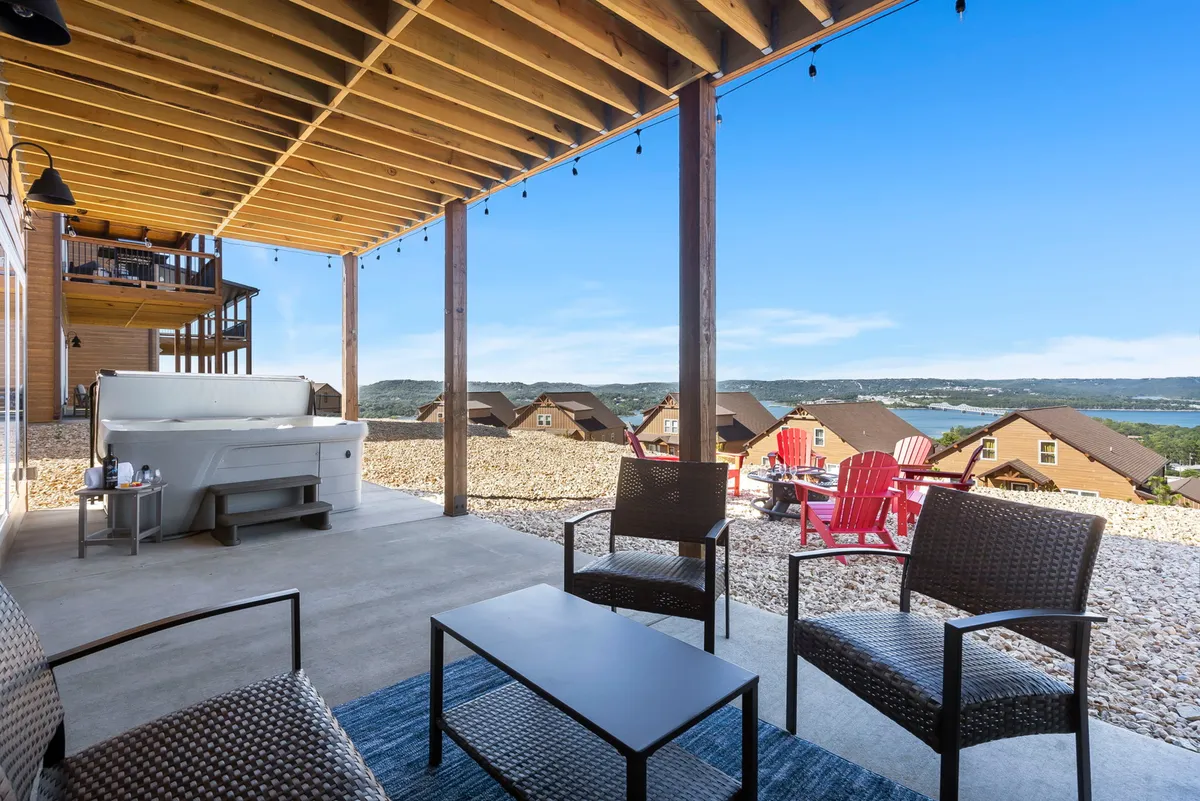 This exterior image showcases a luxurious hot tub setup with red Adirondack chairs and a seating area overlooking rolling hills. The view is expansive and includes a fire pit, with the hot tub acting as the focal point for relaxation. The atmosphere is one of comfort and socializing, perfect for winding down with friends or family while soaking in the scenery.
